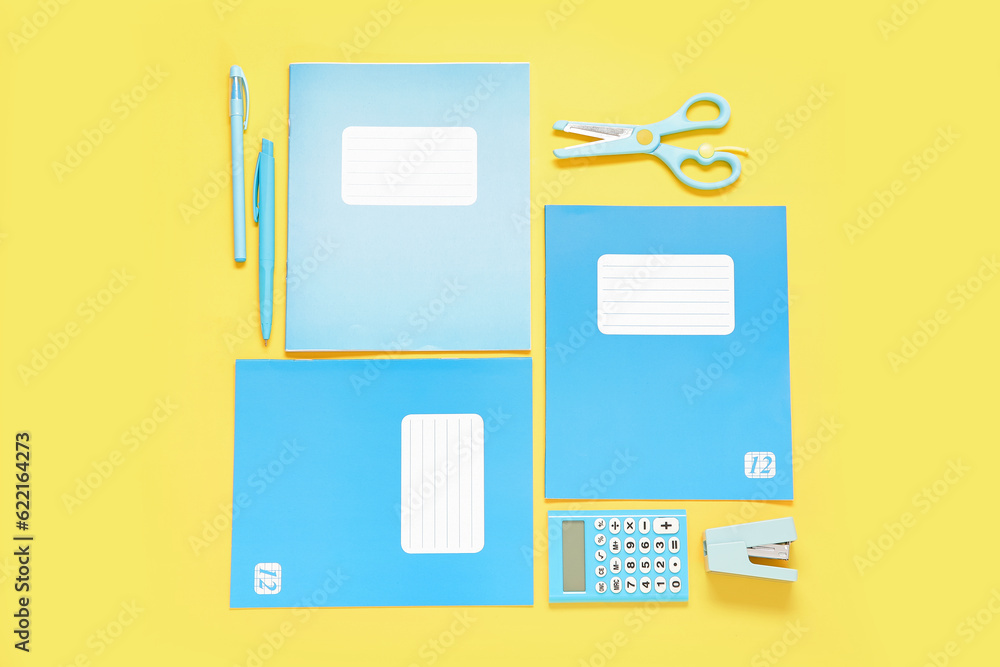 Notebooks with different stationery on yellow background