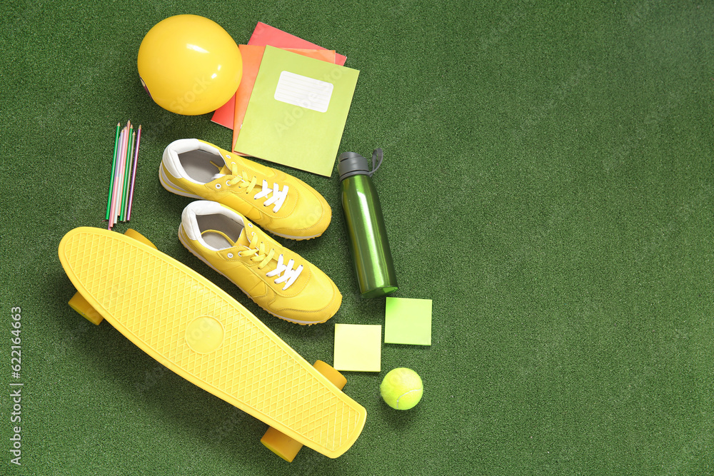 Sneakers with bottle of water, sport equipment and different stationery on color background