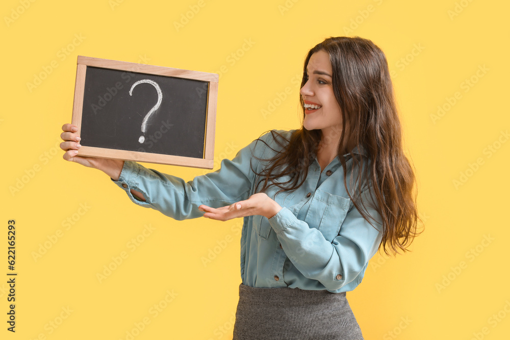 Female teacher holding chalkboard with question mark on yellow background