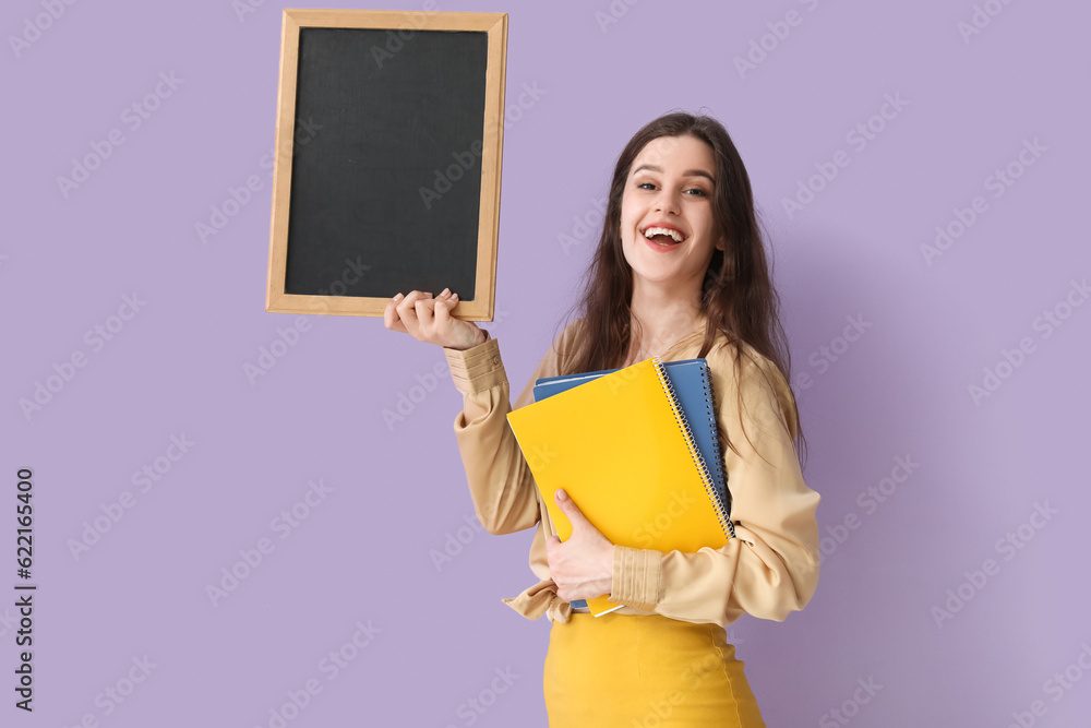 Female teacher with chalkboard and notebooks on lilac background