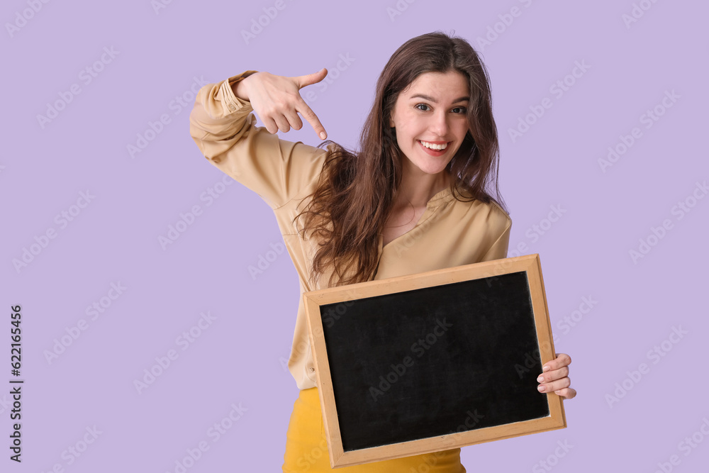 Female teacher pointing at chalkboard on lilac background