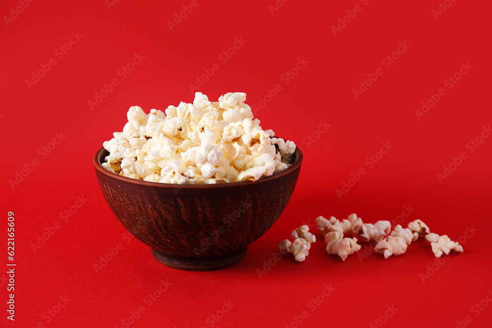 Bowl with tasty popcorn on red background