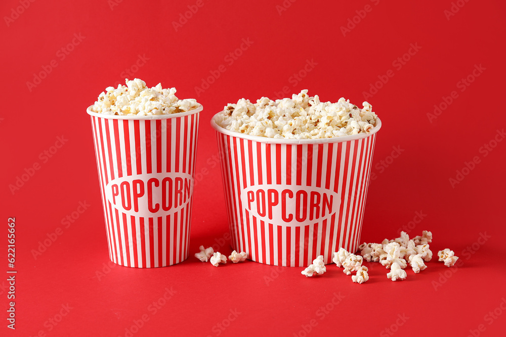 Buckets with tasty popcorn on red background