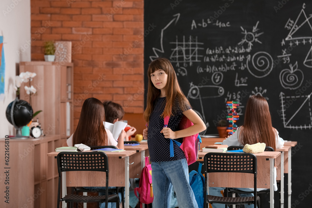 Little girl with backpack in classroom