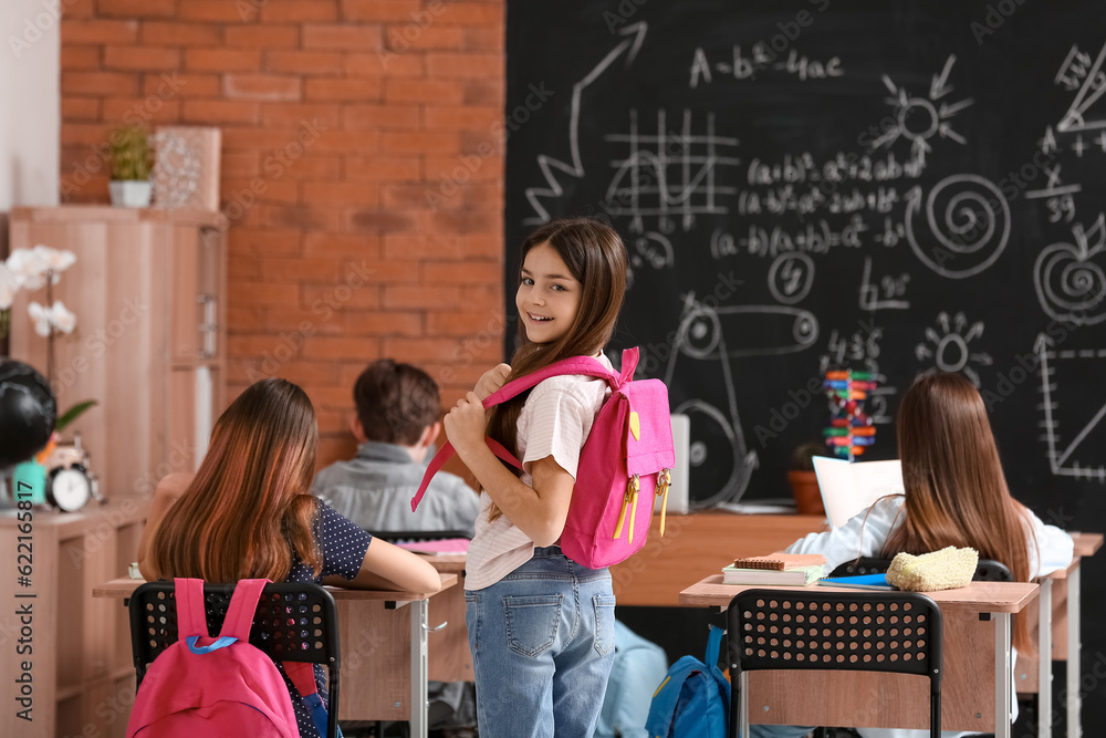 Little girl with backpack in classroom