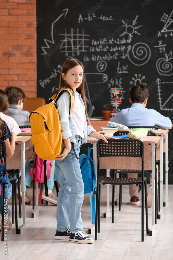 Little girl with backpack in classroom