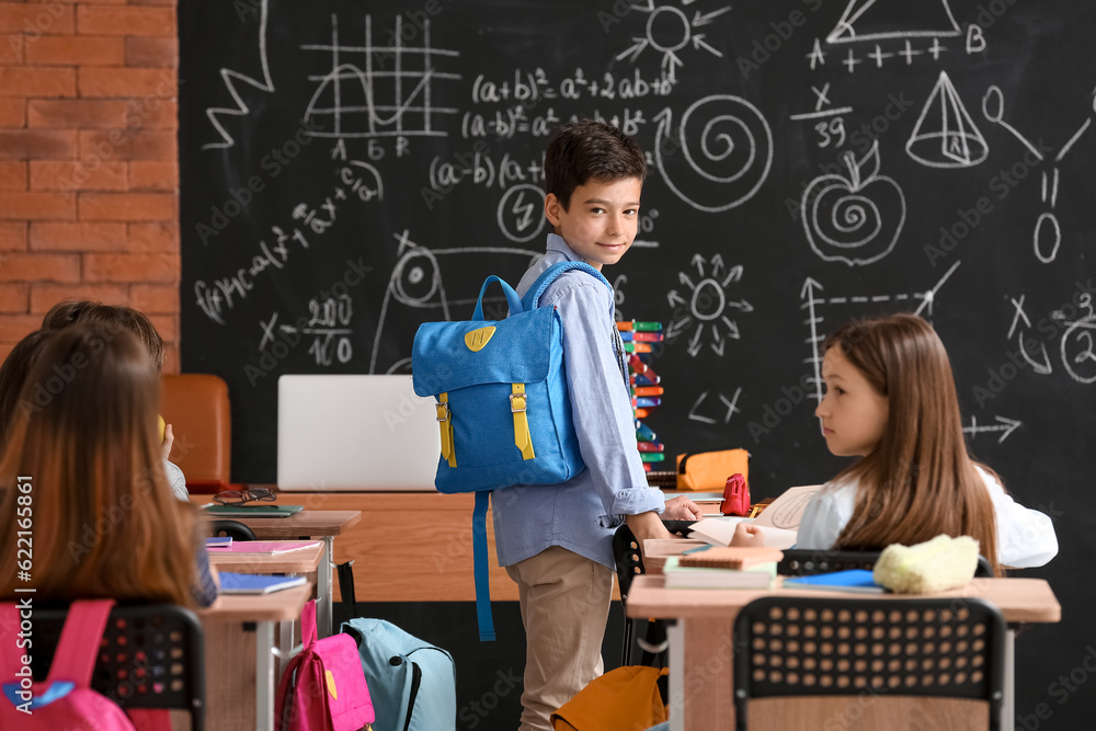 Little boy with backpack in classroom