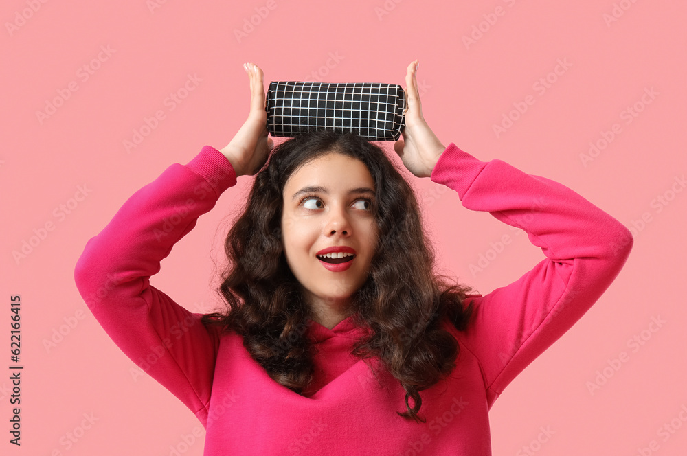 Female student with pencil case on pink background