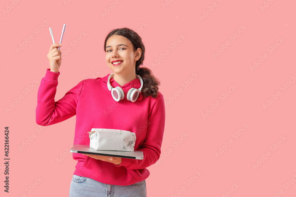 Female student with pencil case and laptop on pink background