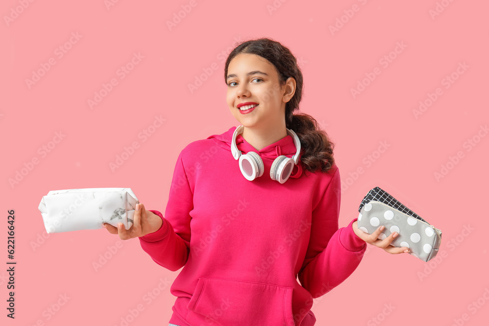 Female student with pencil cases on pink background