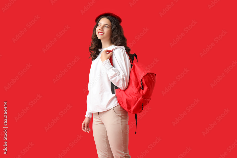 Female student with backpack on red background