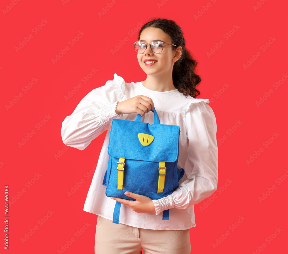 Female student with backpack on red background