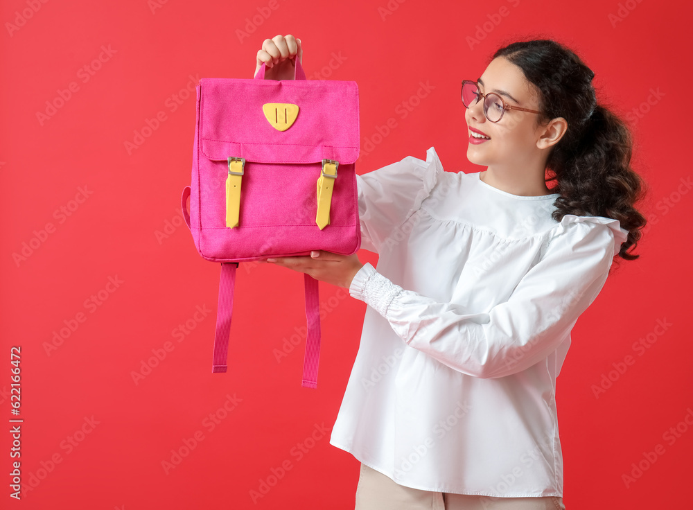 Female student with backpack on red background