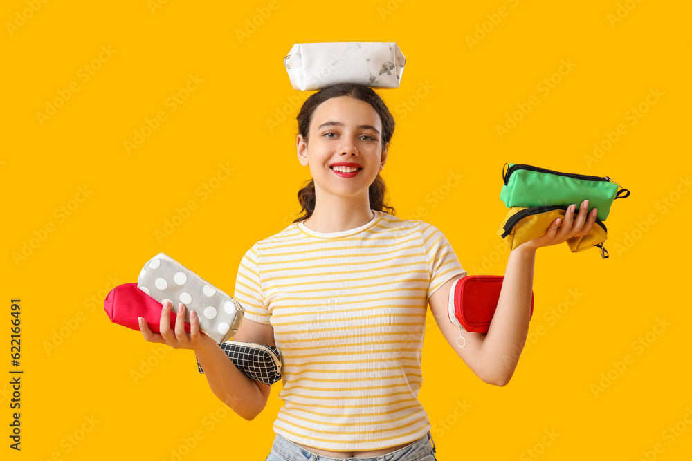 Female student with pencil cases on yellow background