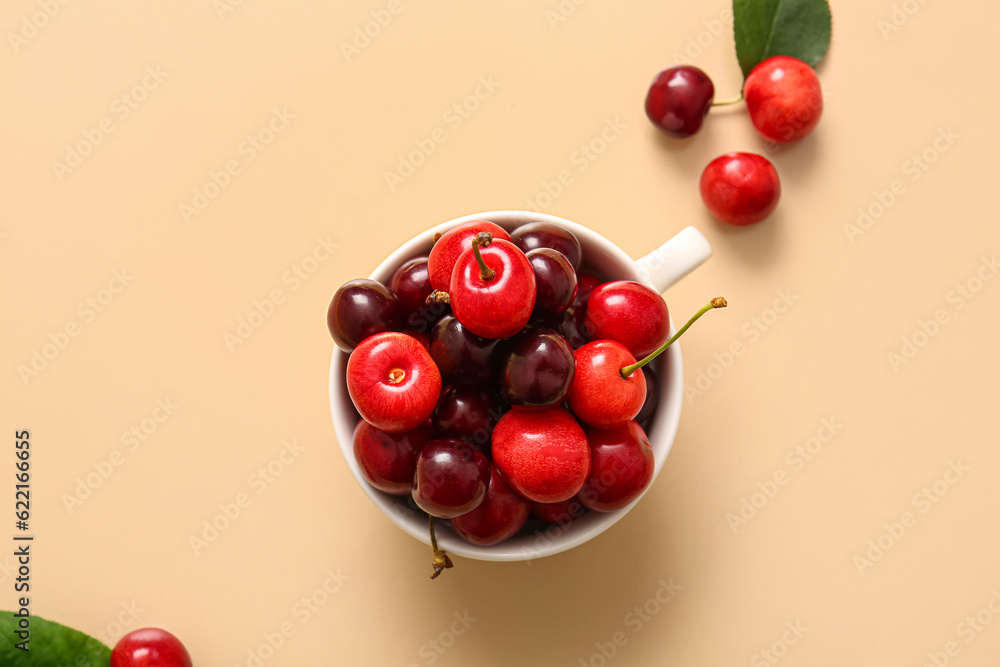 Cup with sweet cherries on orange background