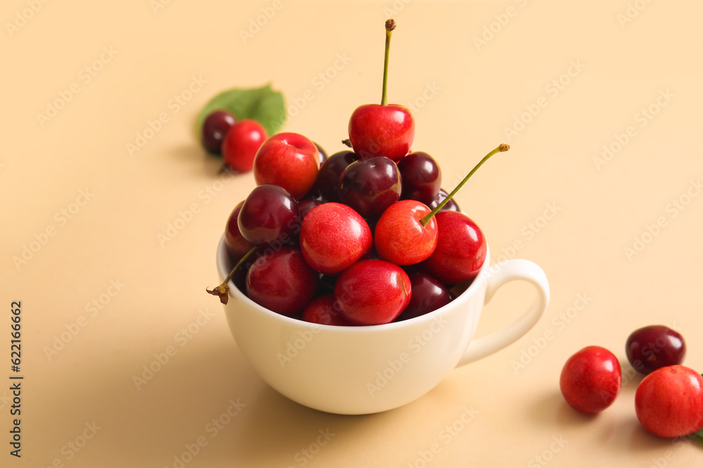 Cup with sweet cherries on orange background