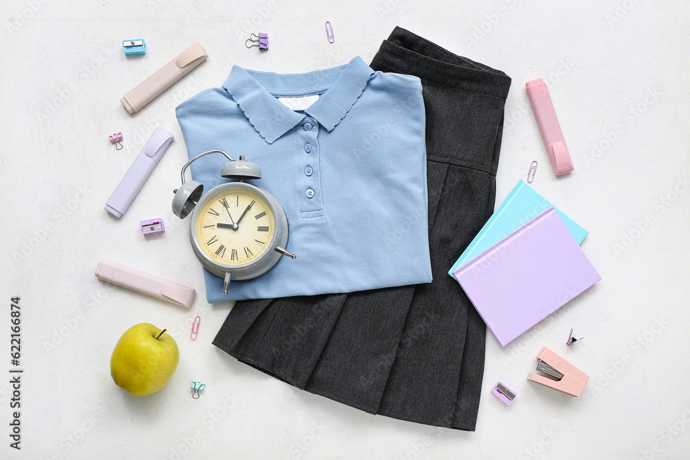 Different stationery with alarm clock and stylish school uniform on white background