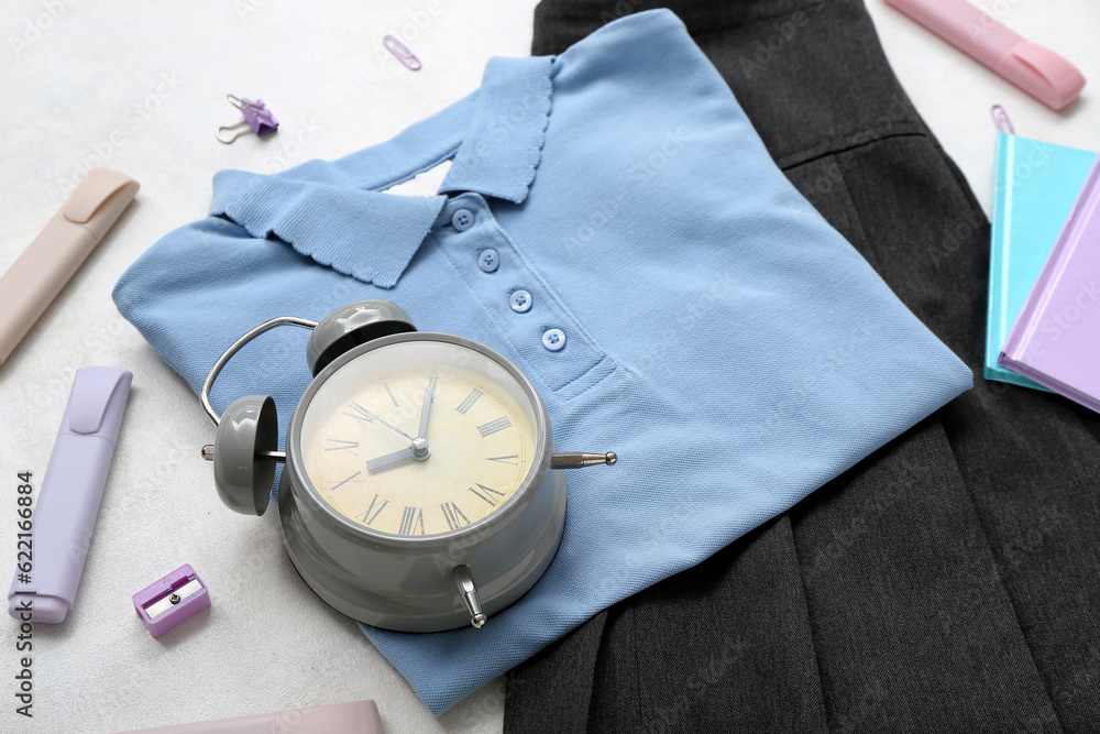 Different stationery with alarm clock and stylish school uniform on white background