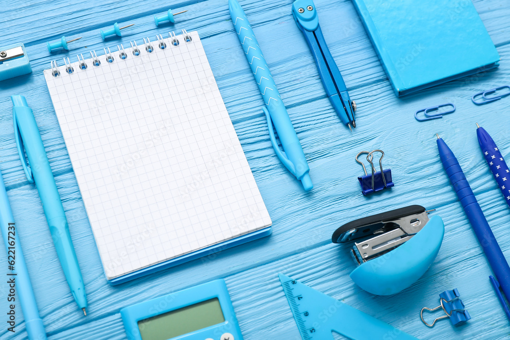 Blank notebook and different stationery on blue wooden background