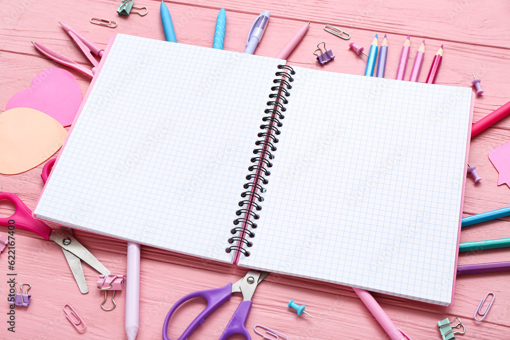 Blank notebook and different stationery on pink wooden background