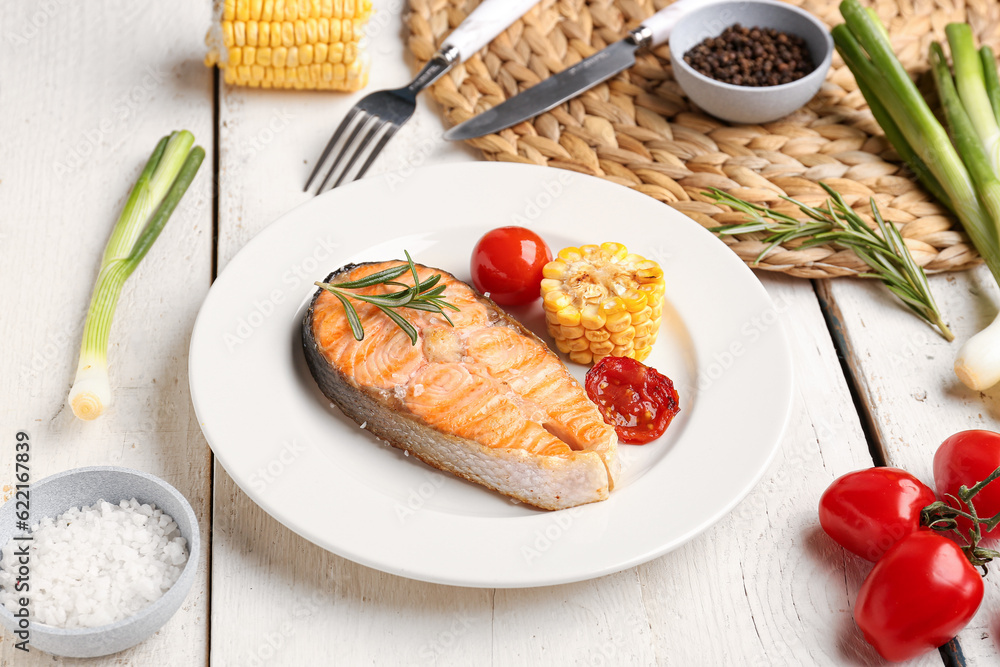 Plate with tasty grilled salmon steak on light wooden background