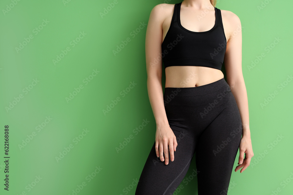 Young woman in sportswear on green background