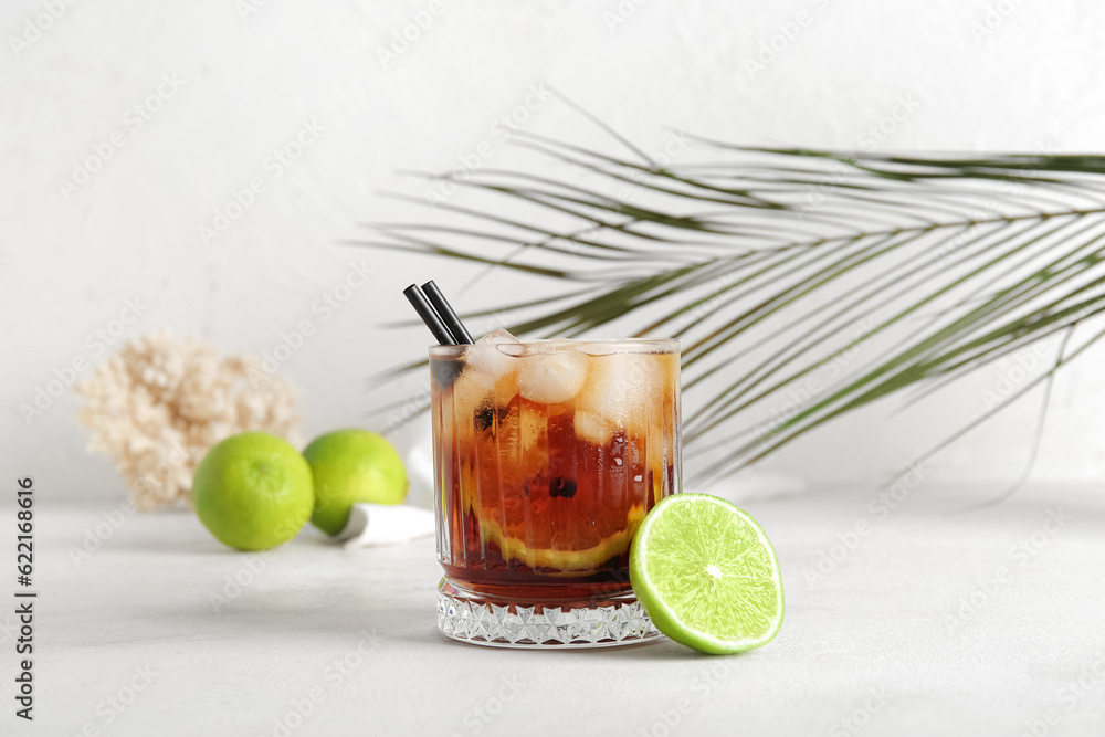 Glass of cold Cuba Libre cocktail and palm leaf on white background