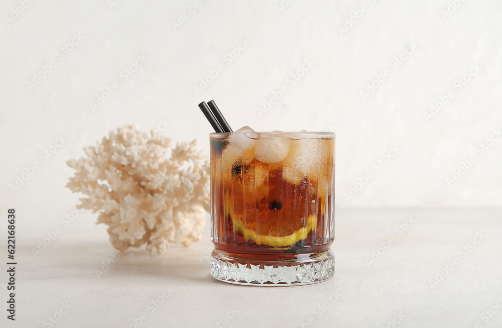 Glass of cold Cuba Libre cocktail and coral on white background