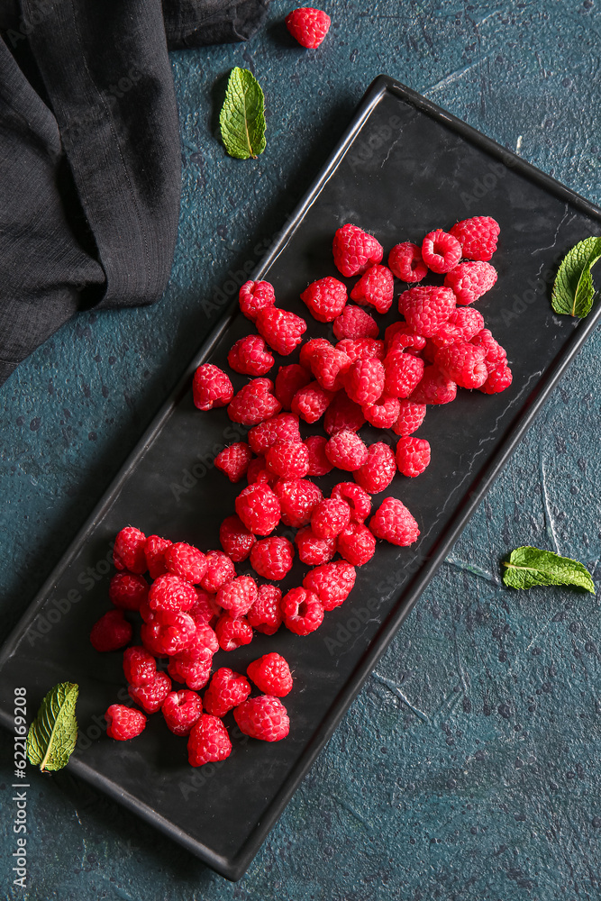 Tray with fresh raspberries on dark table