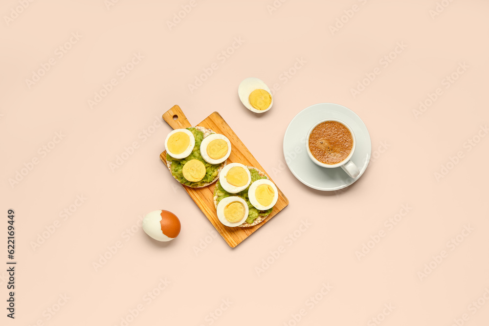 Wooden board of rice crackers with boiled eggs and avocado on pink background