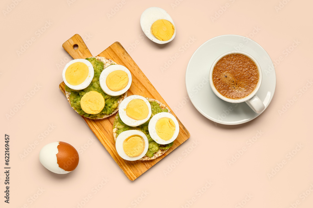 Wooden board of rice crackers with boiled eggs and avocado on pink background