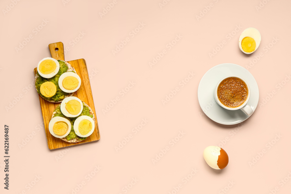 Wooden board of rice crackers with boiled eggs and avocado on pink background