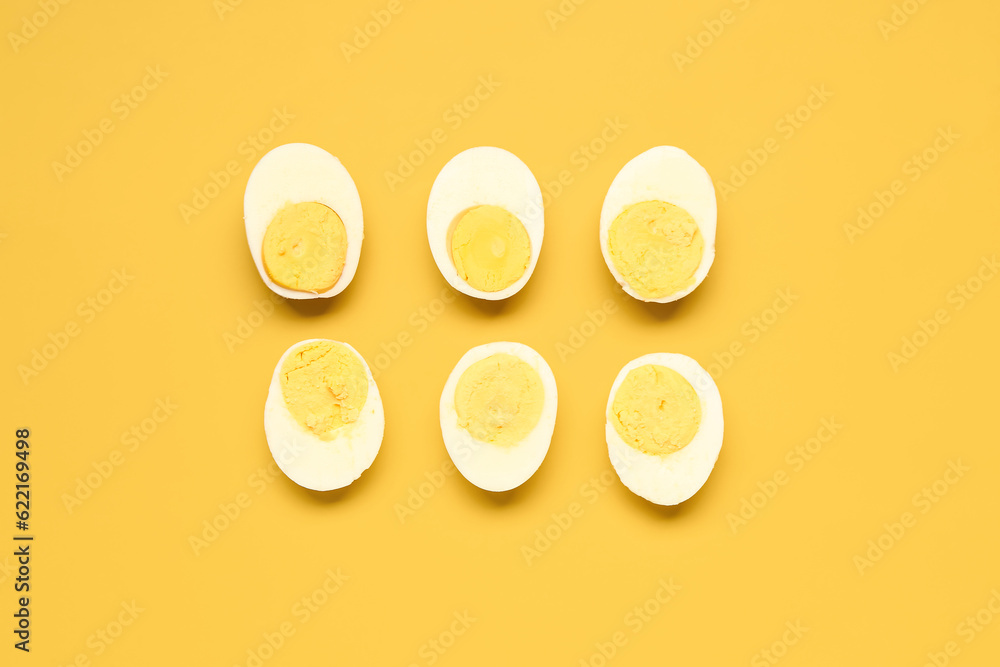 Halves of tasty boiled eggs on yellow background