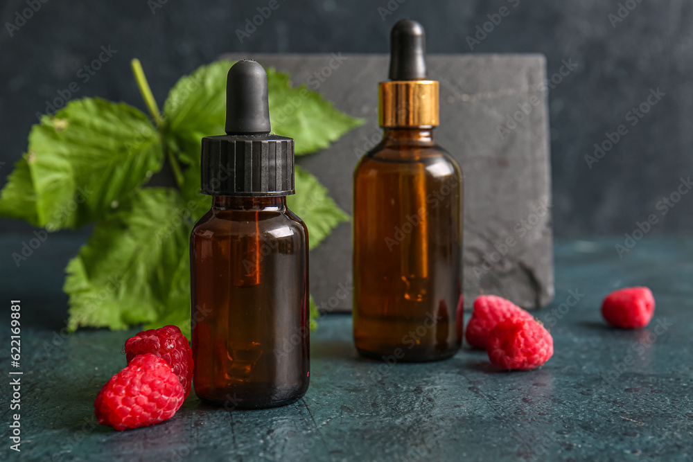 Bottles of cosmetic raspberry oil on dark background