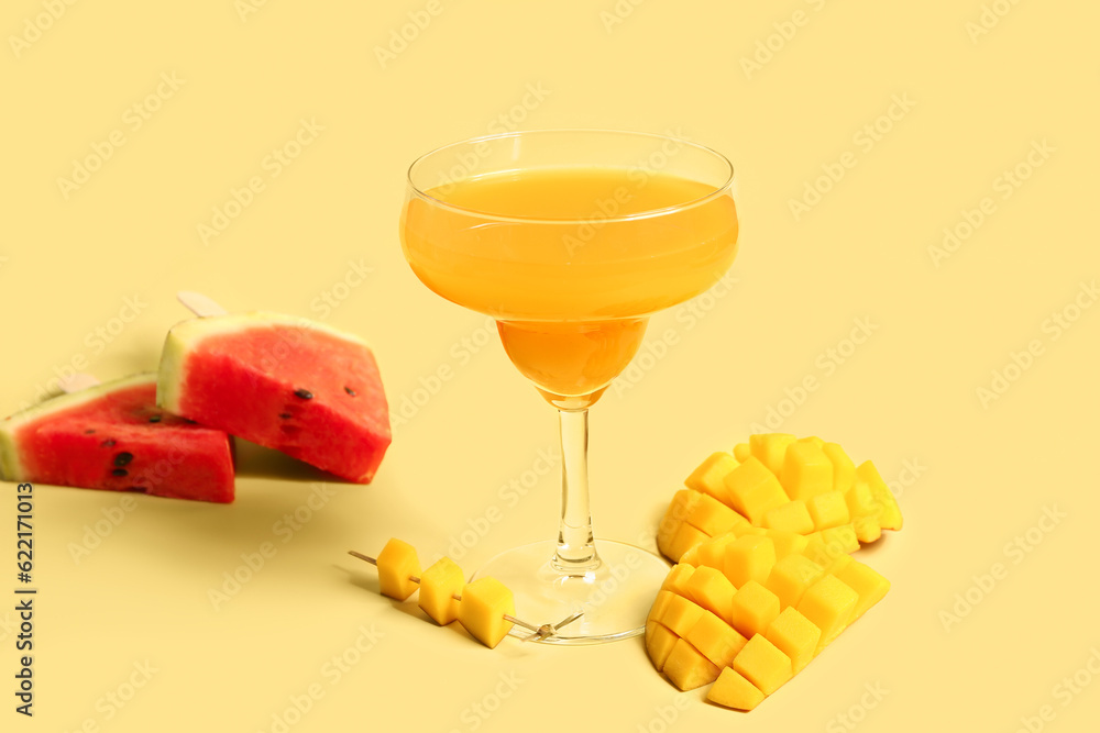 Glass of fresh mango juice and watermelon on yellow background