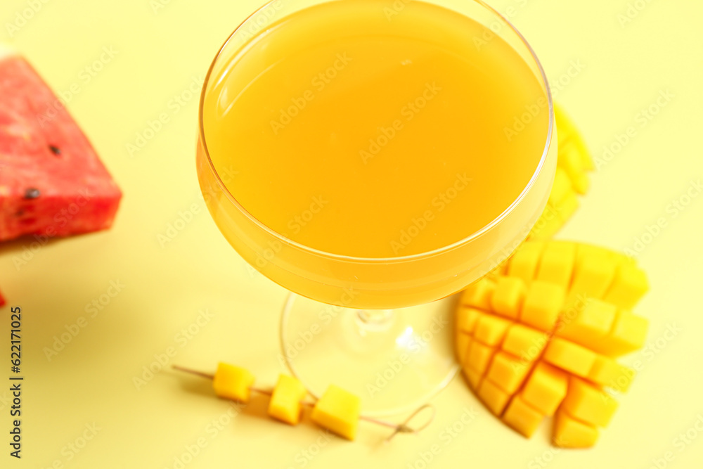 Glass of fresh mango juice and watermelon on yellow background