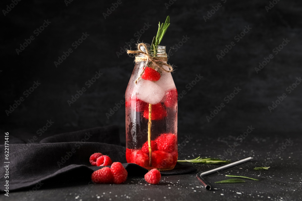 Bottle of fresh raspberry lemonade with rosemary on black background