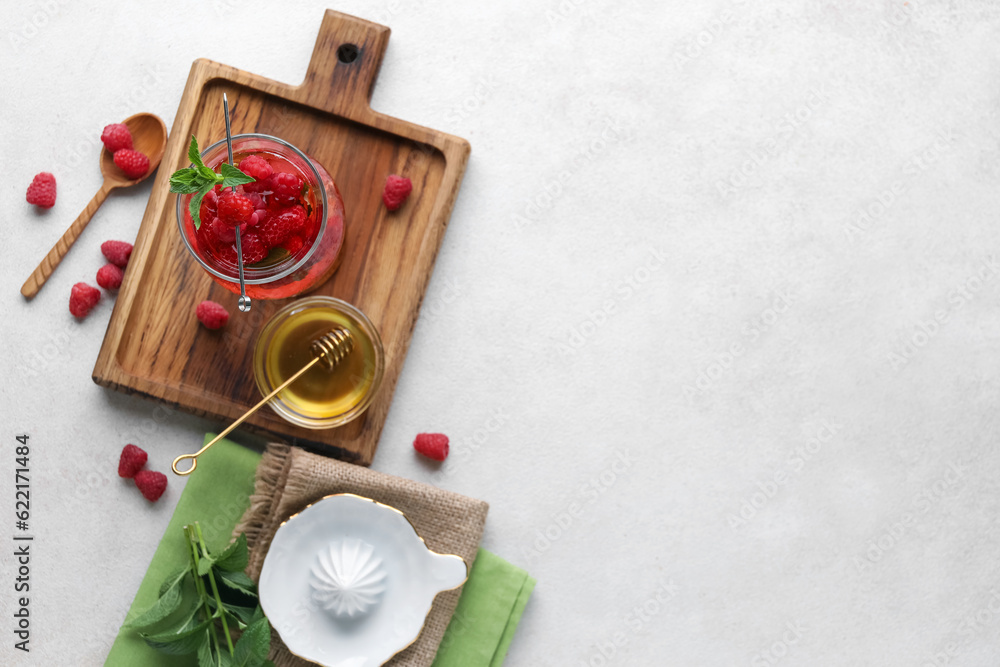 Glass of fresh raspberry lemonade and bowl with honey on white background