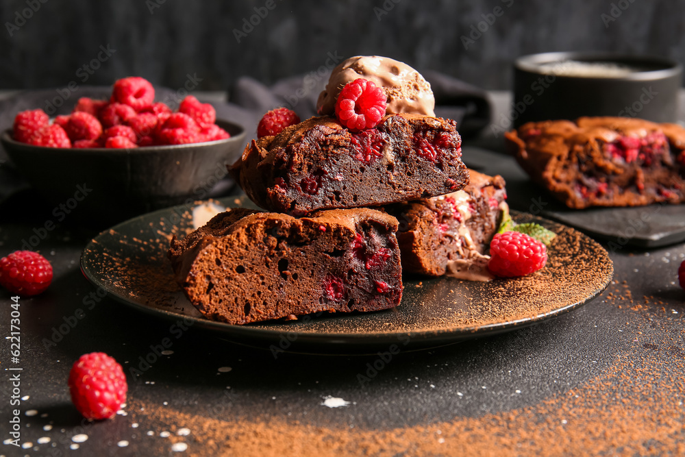 Plate with pieces of raspberry chocolate brownie and ice-cream on black background