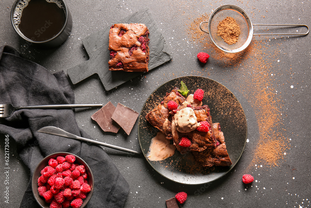 Plate and board with raspberry chocolate brownie on black background