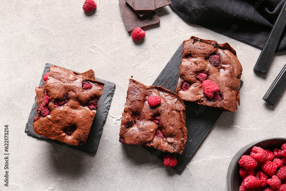 Boards with pieces of raspberry chocolate brownie on grey table