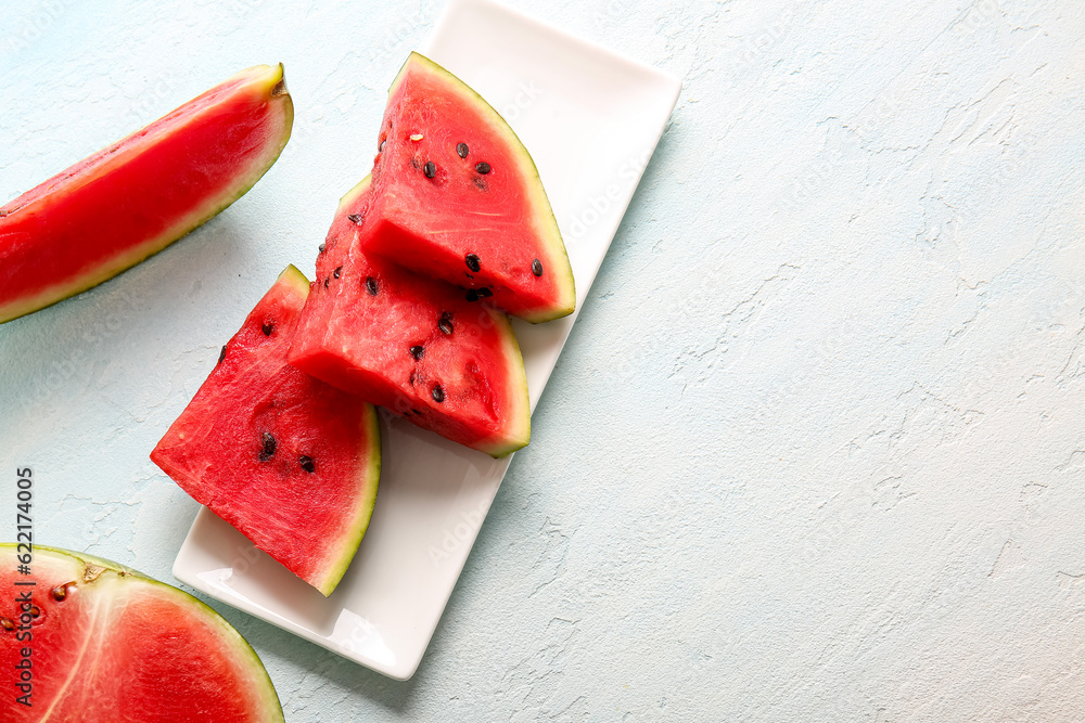 Plate with pieces of fresh watermelon on light blue table