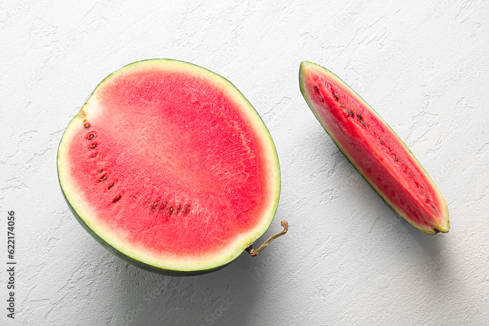 Half of fresh watermelon with piece on light blue background