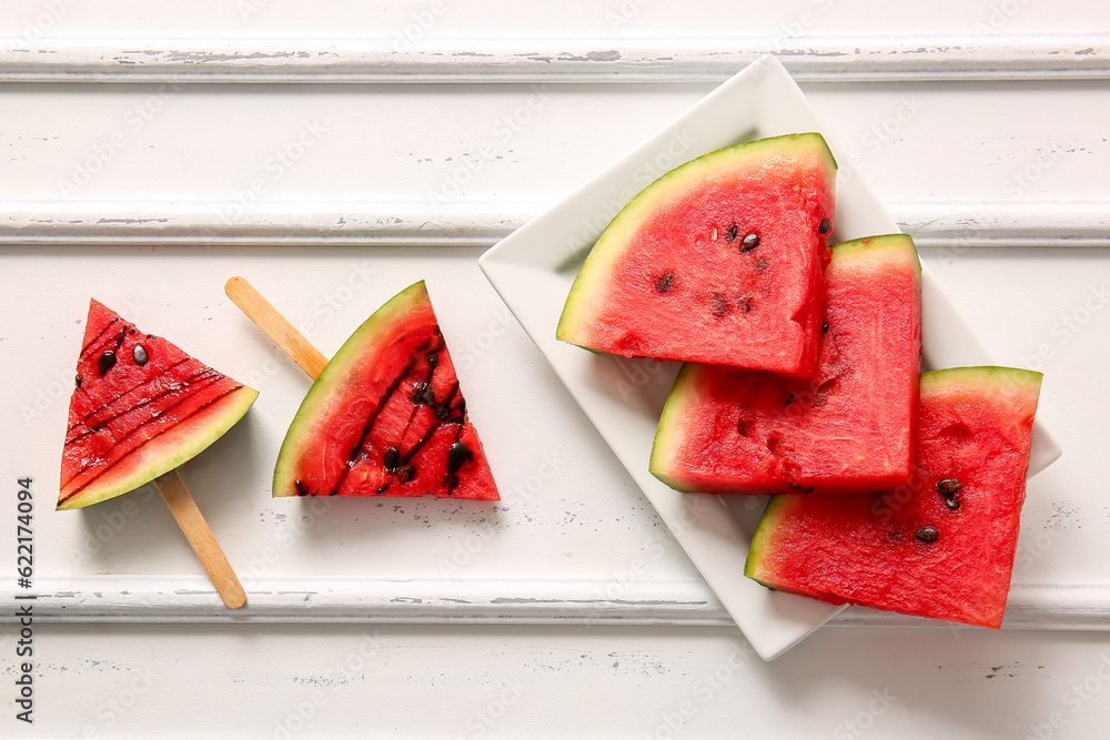 Sweet watermelon sticks and plate with pieces on white table