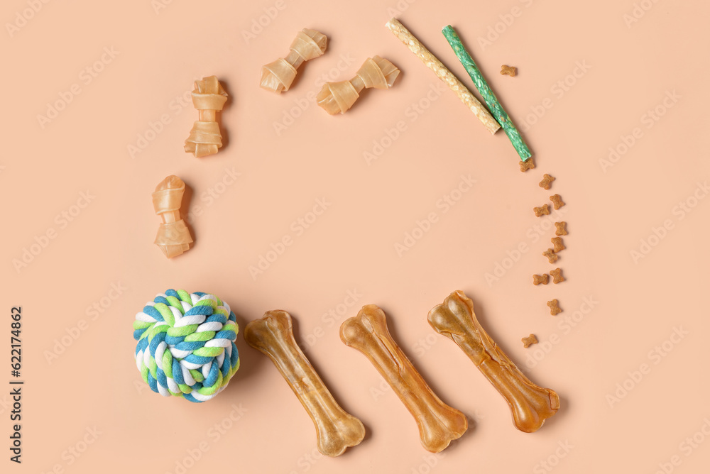 Frame made of different dog treats and toy ball on color background