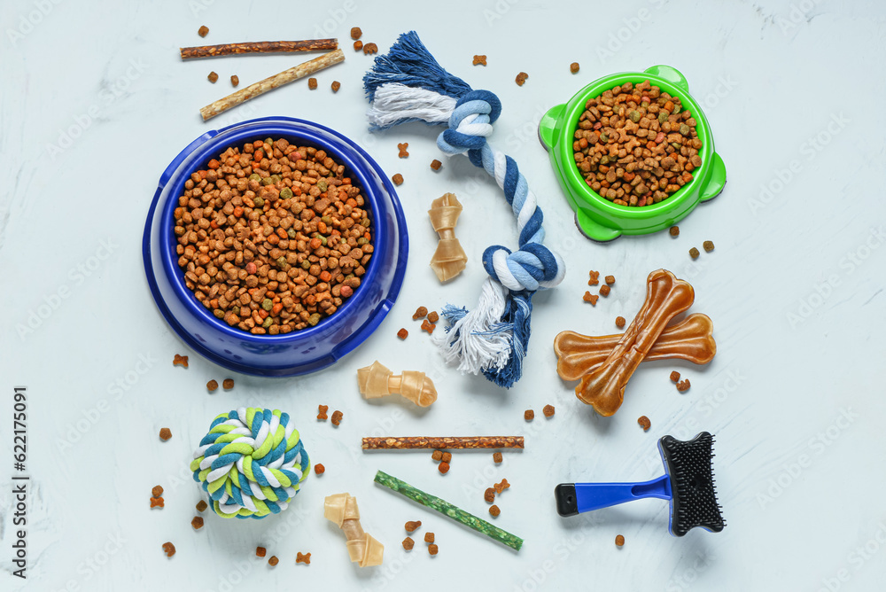 Composition with different dog food and pet care accessories on light background