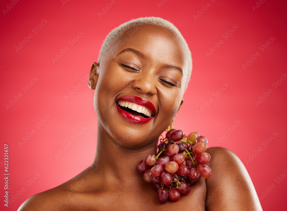 Beauty, smile and grapes with a model black woman in studio on a red background for health or nutrit