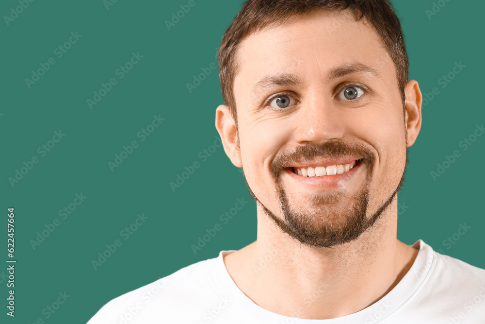 Young bearded man smiling on green background, closeup