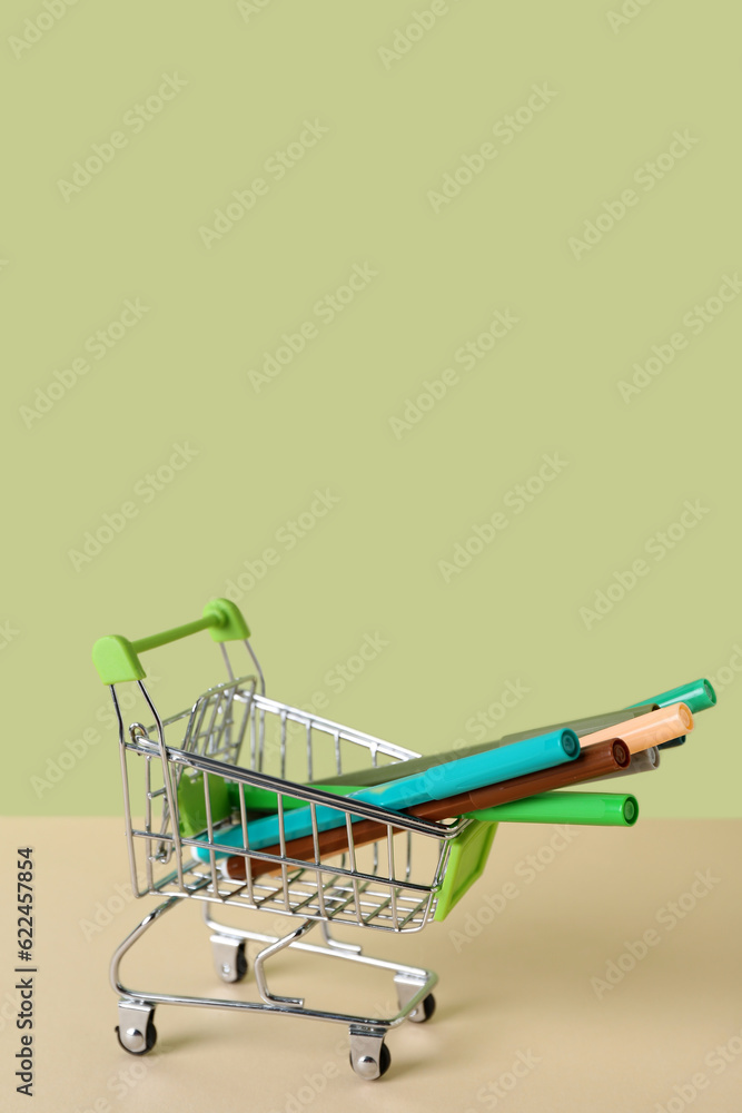 Shopping cart with felt-tip pens on color background