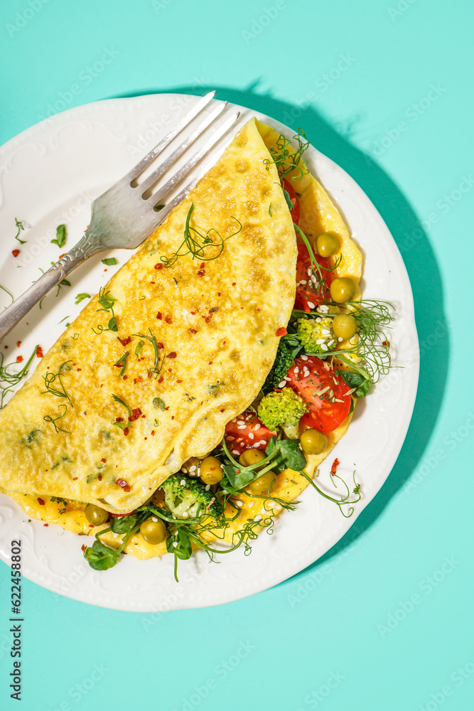 Tasty omelet with vegetables on blue background